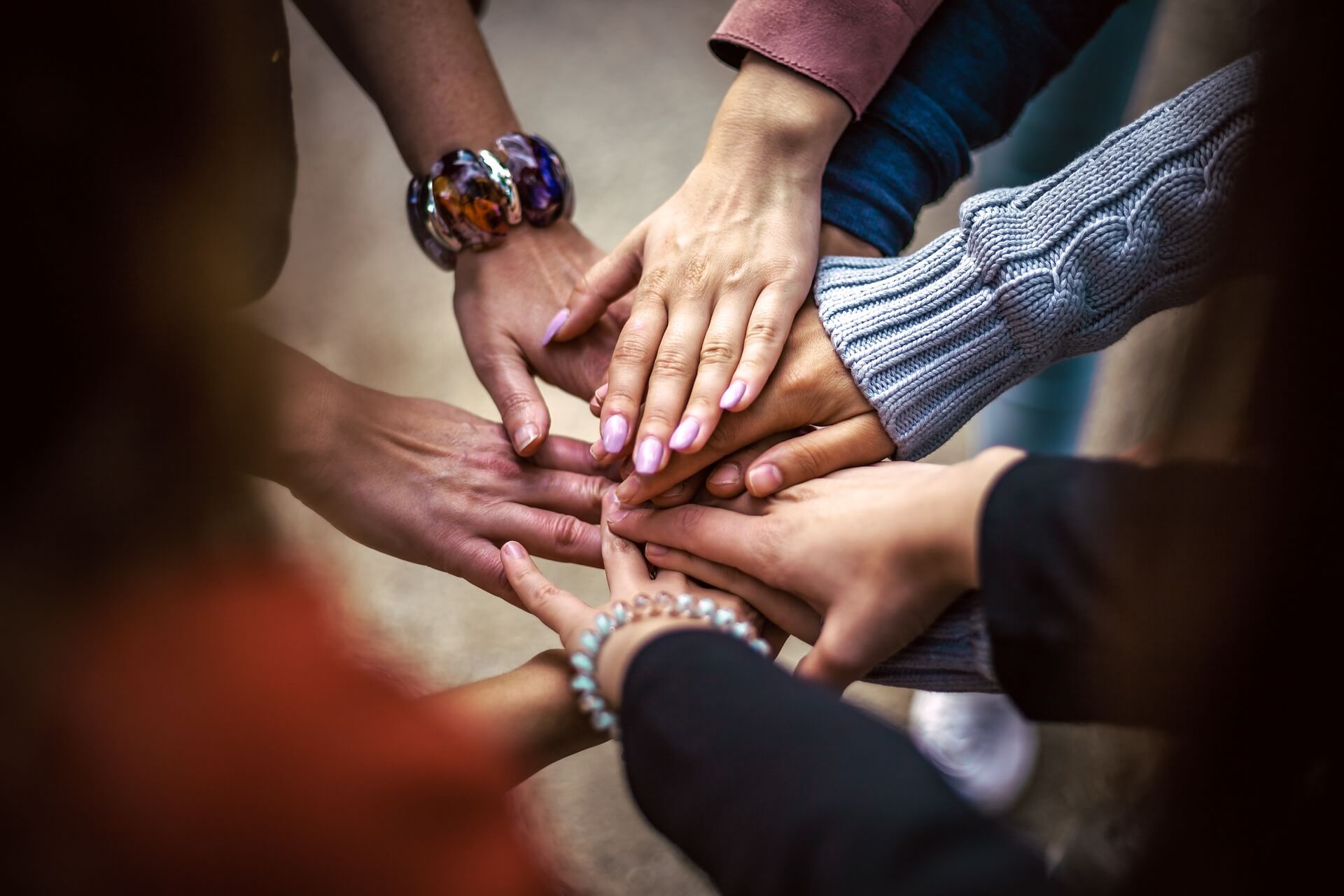 Viele Hände von alten und jungen Menschen, die im Kreis stehen, werden in der Mitte zusammengelegt